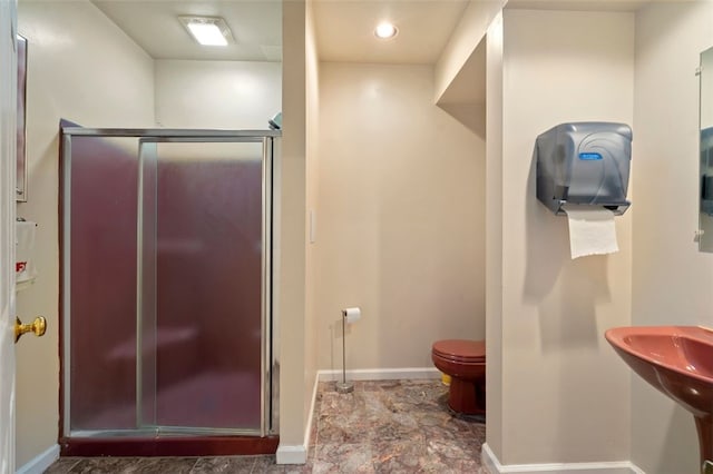 full bathroom featuring a stall shower, toilet, a sink, and baseboards