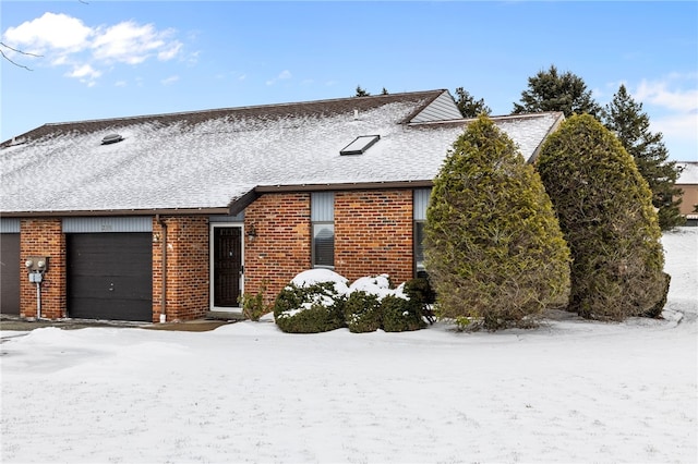 townhome / multi-family property with a garage, brick siding, and roof with shingles