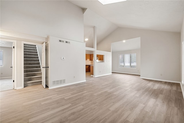 unfurnished living room with high vaulted ceiling, visible vents, baseboards, stairs, and light wood finished floors