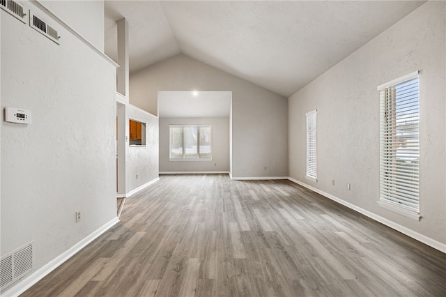 unfurnished living room featuring lofted ceiling, wood finished floors, and visible vents