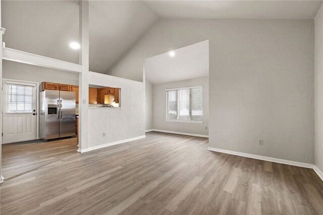 unfurnished living room featuring light wood-type flooring, a wealth of natural light, and baseboards