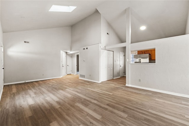 unfurnished living room featuring light wood-type flooring, a skylight, visible vents, and baseboards