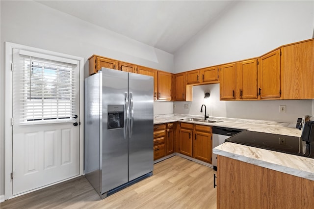 kitchen with appliances with stainless steel finishes, brown cabinetry, light countertops, and a sink