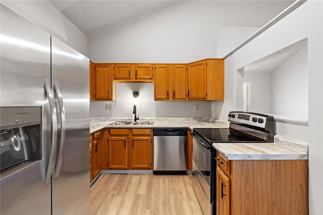 kitchen with light wood-style flooring, stainless steel appliances, a sink, vaulted ceiling, and light countertops