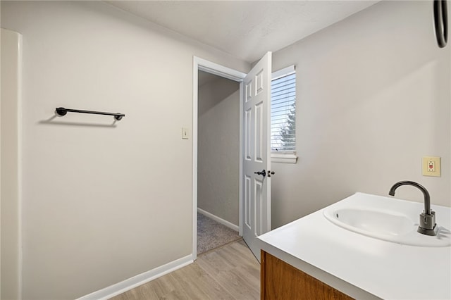 bathroom with wood finished floors, vanity, and baseboards