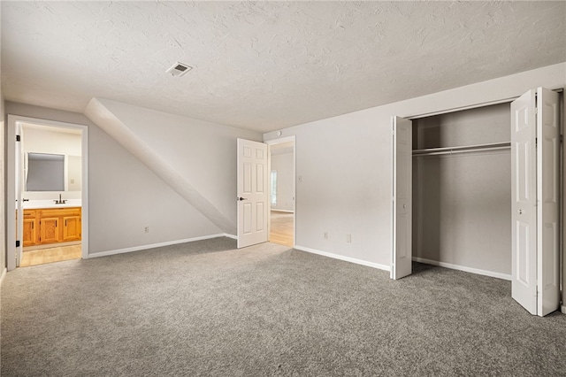 unfurnished bedroom with visible vents, baseboards, a textured ceiling, carpet floors, and a closet