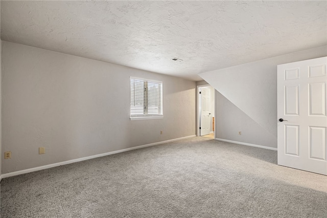 carpeted spare room featuring a textured ceiling, visible vents, and baseboards