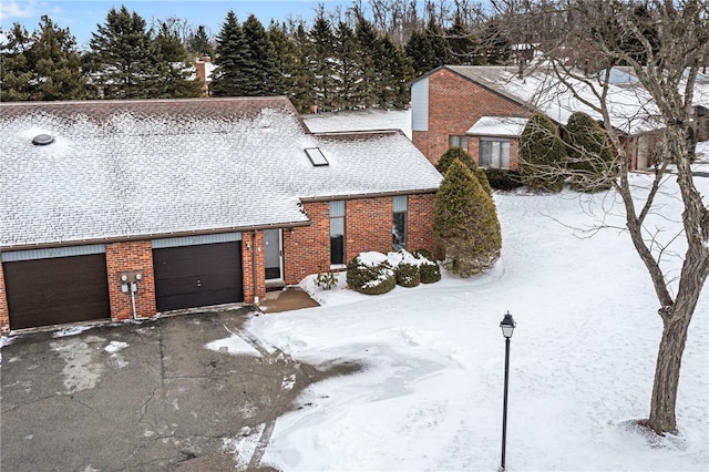 view of front of home with an attached garage, roof with shingles, aphalt driveway, and brick siding