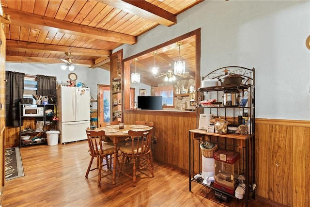 dining area with a ceiling fan, wainscoting, wood ceiling, vaulted ceiling with beams, and wood walls