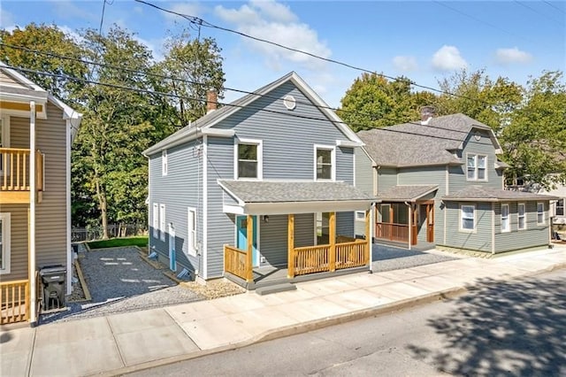 view of front of home featuring covered porch, driveway, and a chimney