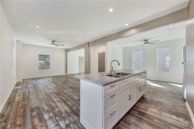 kitchen with an island with sink, dark wood-style floors, open floor plan, white cabinetry, and a sink