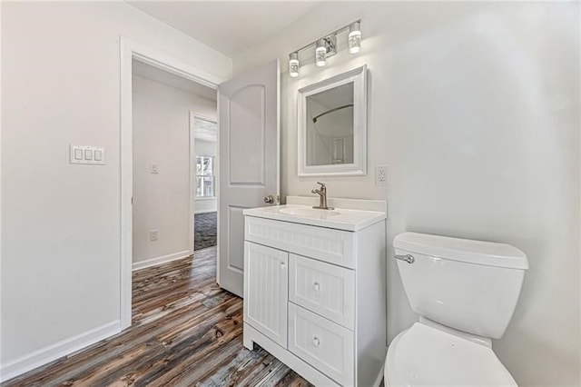 bathroom featuring toilet, wood finished floors, vanity, and baseboards