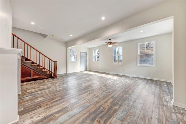 unfurnished living room featuring stairs, baseboards, wood finished floors, and recessed lighting