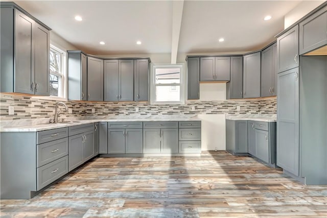 kitchen with beam ceiling, backsplash, a sink, and gray cabinetry