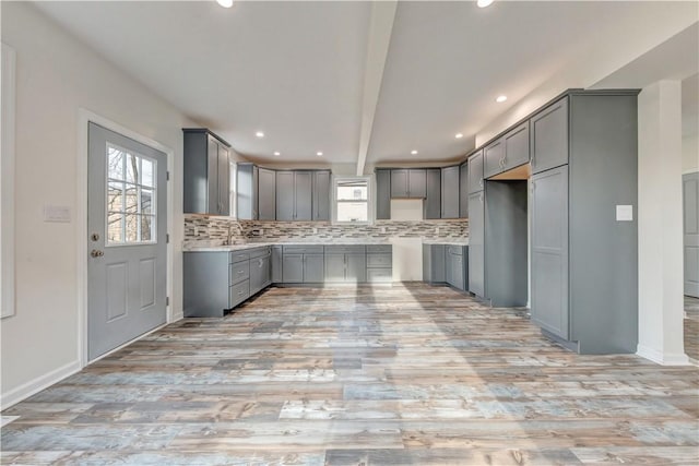 kitchen with light countertops, tasteful backsplash, beamed ceiling, and gray cabinetry