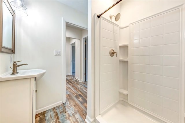 bathroom with a stall shower, baseboards, wood finished floors, and vanity