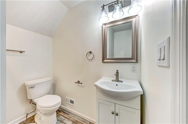 half bathroom featuring visible vents, toilet, vanity, wood finished floors, and baseboards