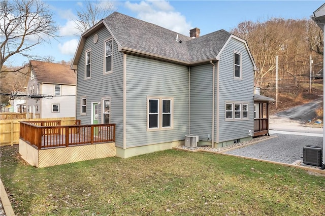 rear view of house featuring central AC, a lawn, a deck, and roof with shingles