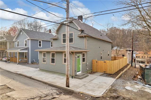 rear view of house with a patio, a shingled roof, and fence