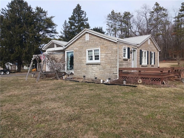 rear view of property with a yard, metal roof, and a wooden deck