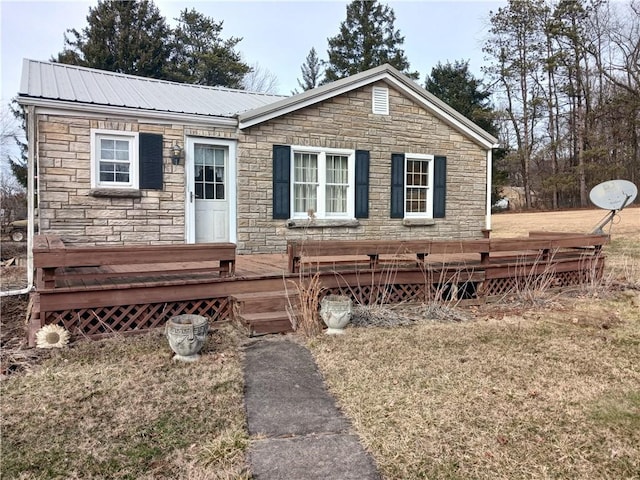 view of front facade with a deck, metal roof, and a front lawn