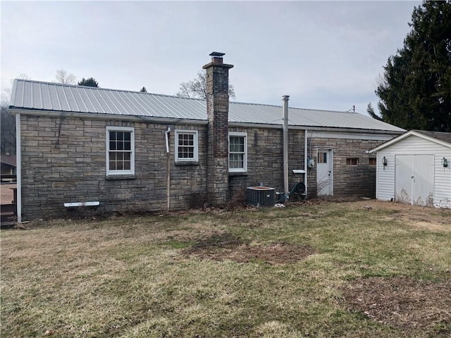 rear view of house featuring a yard, metal roof, a shed, stone siding, and an outdoor structure