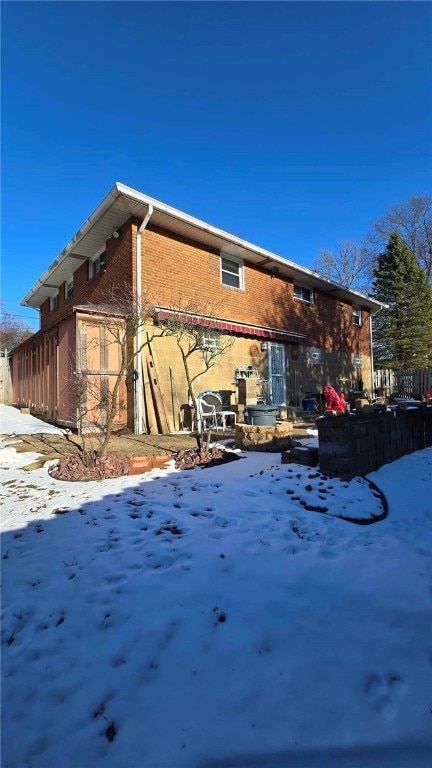 view of snow covered exterior with a patio and brick siding