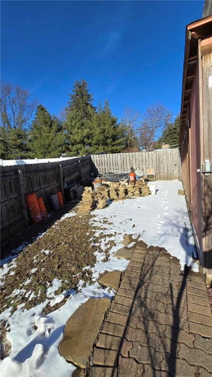 snowy yard featuring a fenced backyard