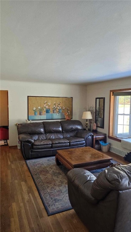 living area featuring dark wood-type flooring, a textured ceiling, and baseboards