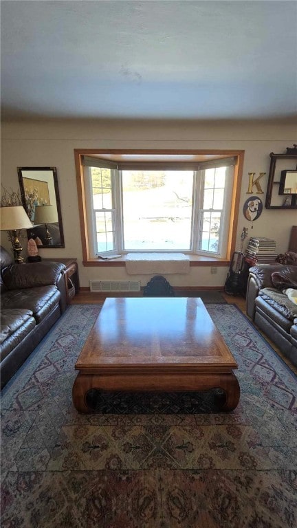 living area featuring a healthy amount of sunlight, visible vents, and wood finished floors