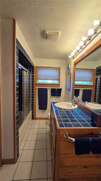 full bath featuring toilet, a shower with door, tile patterned floors, a textured ceiling, and vanity