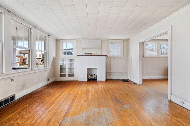 unfurnished living room with visible vents, light wood-style flooring, and baseboards