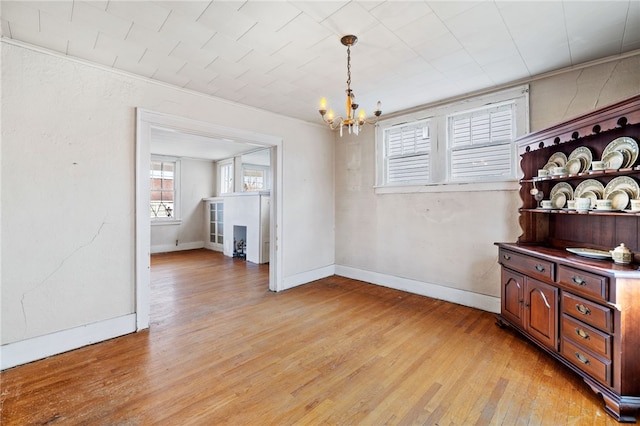 dining space featuring crown molding, baseboards, light wood-style flooring, and a notable chandelier