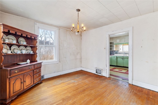 dining space featuring light wood-style floors, baseboards, visible vents, and a notable chandelier