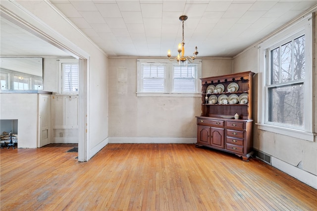 dining area featuring light wood-type flooring, a healthy amount of sunlight, a notable chandelier, and visible vents