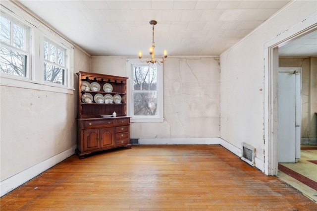 dining area with an inviting chandelier, light wood-style flooring, visible vents, and baseboards