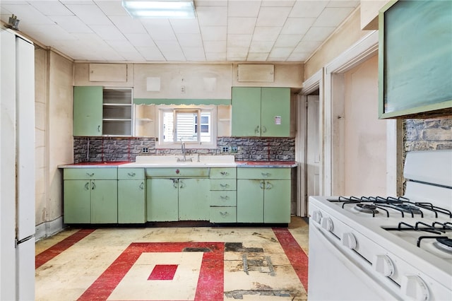 kitchen featuring green cabinets, white gas stove, a sink, and decorative backsplash