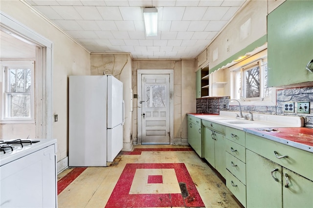 kitchen with white appliances, a sink, light countertops, open shelves, and green cabinetry