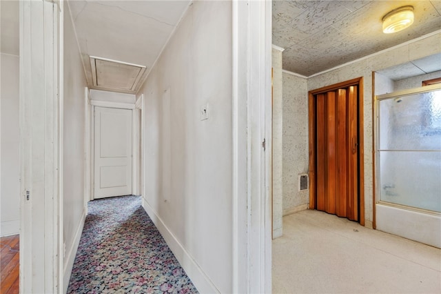 hall with carpet floors, attic access, visible vents, and baseboards