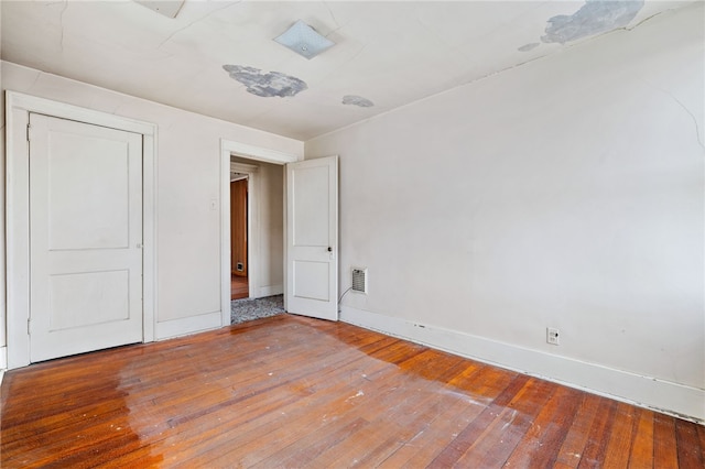 unfurnished bedroom with wood finished floors, visible vents, and baseboards