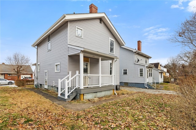 rear view of house featuring a porch and a chimney