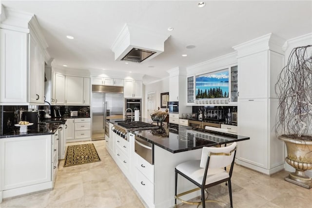 kitchen with white cabinets, a kitchen island, appliances with stainless steel finishes, a breakfast bar, and a warming drawer