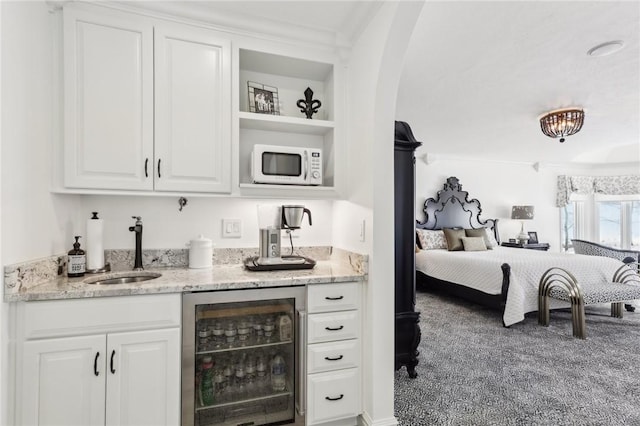 bar featuring arched walkways, white microwave, wine cooler, wet bar, and a sink