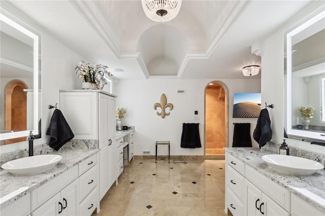 full bath featuring two vanities, a raised ceiling, and a sink