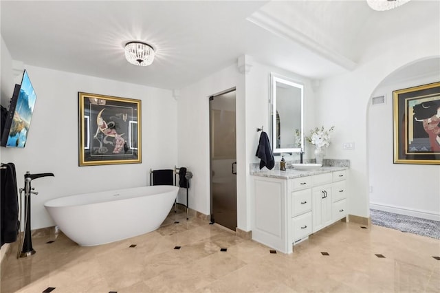 full bath featuring visible vents, a freestanding tub, vanity, and baseboards