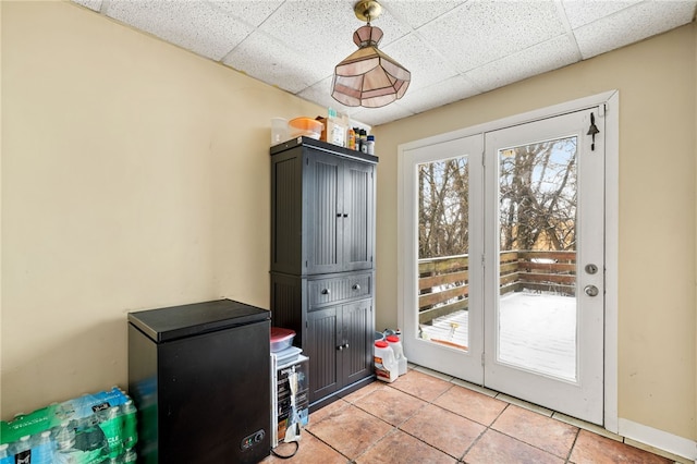 doorway featuring a paneled ceiling, baseboards, and light tile patterned flooring