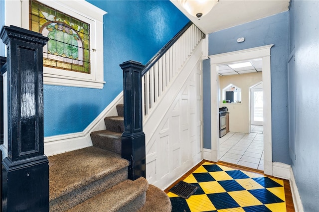 stairs with a drop ceiling, a textured wall, and baseboards