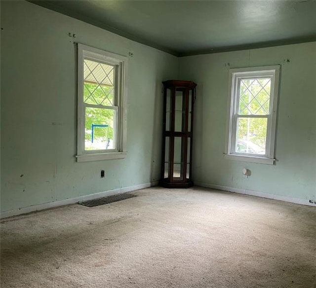 empty room with light colored carpet, visible vents, and baseboards