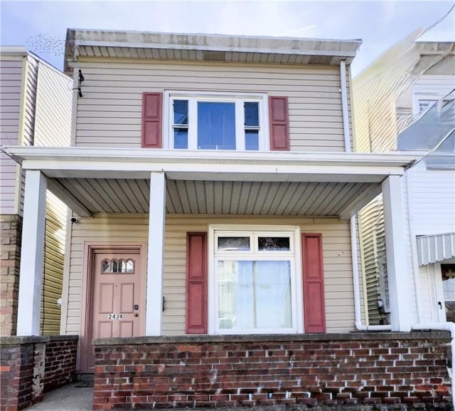 view of property with covered porch and brick siding