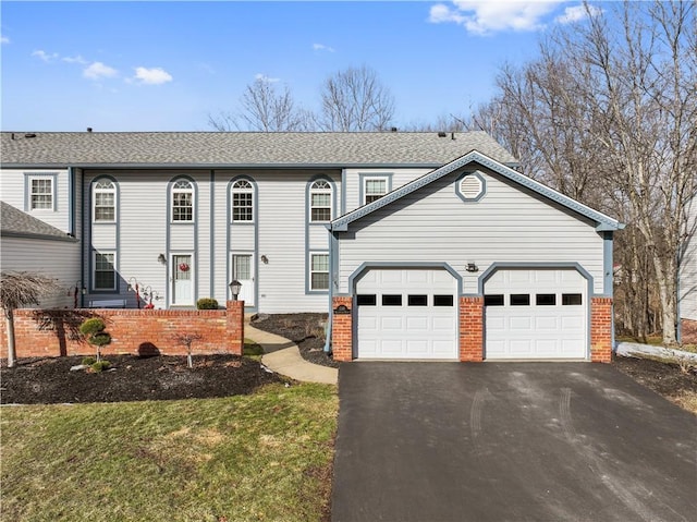 view of front of home featuring aphalt driveway, an attached garage, brick siding, and a front yard